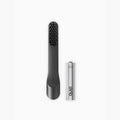 Black handheld tool with bristle head and silver cylindrical battery on a white background